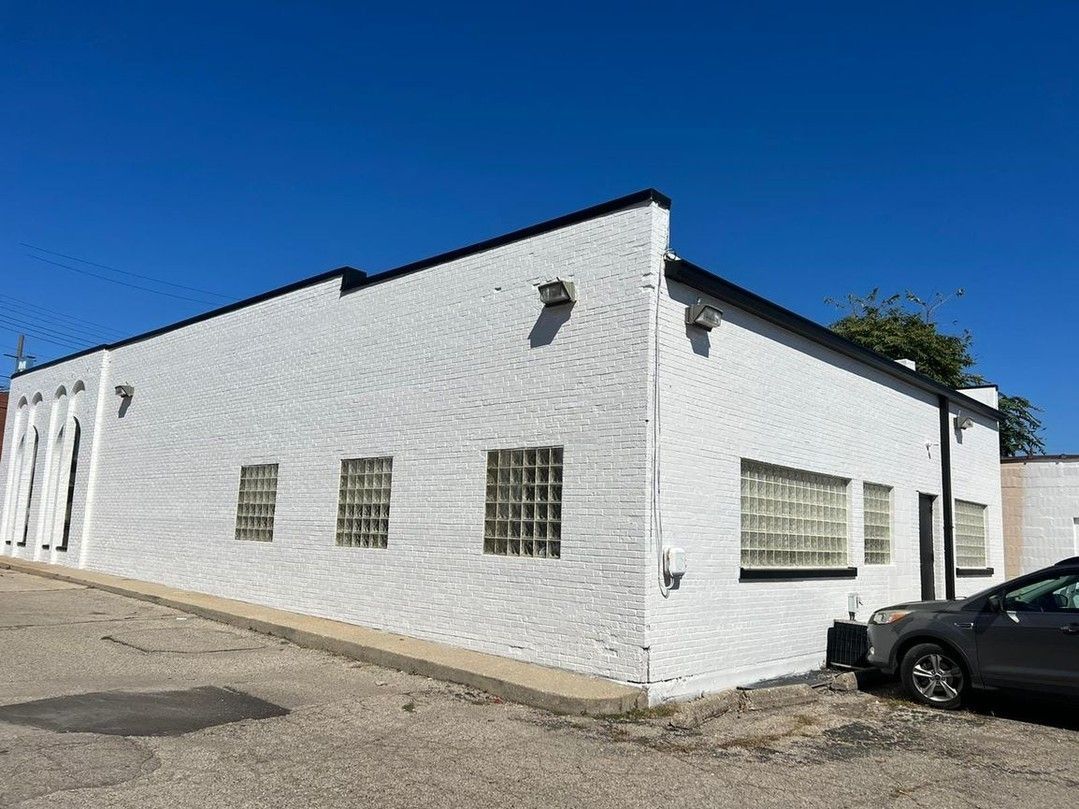 A white building with a car parked in front of it.