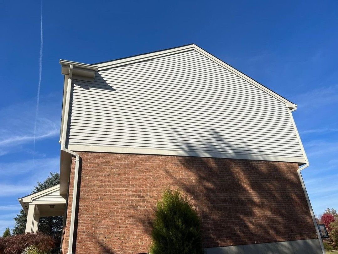 A brick house with a white roof and a blue sky in the background.