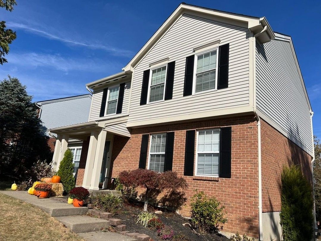 A large brick house with white siding and black shutters.