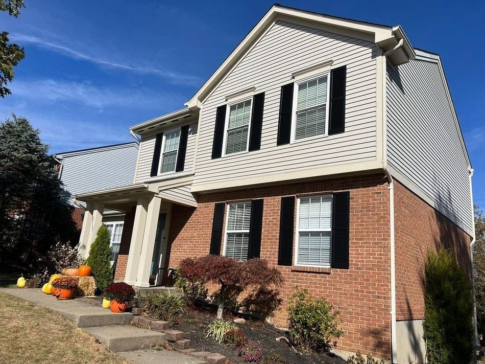 A large brick house with white siding and black shutters.