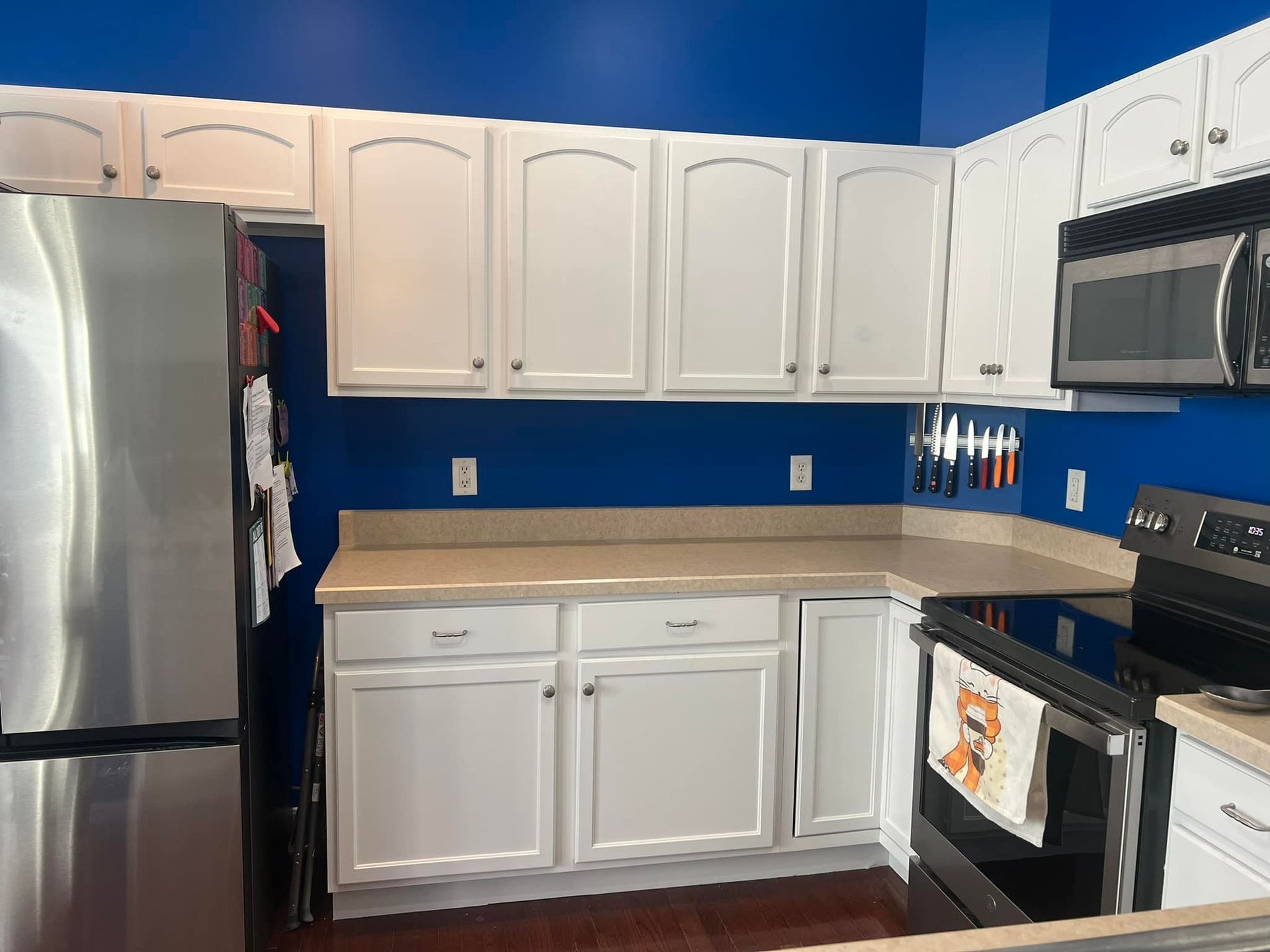 A kitchen with white cabinets , stainless steel appliances and blue walls