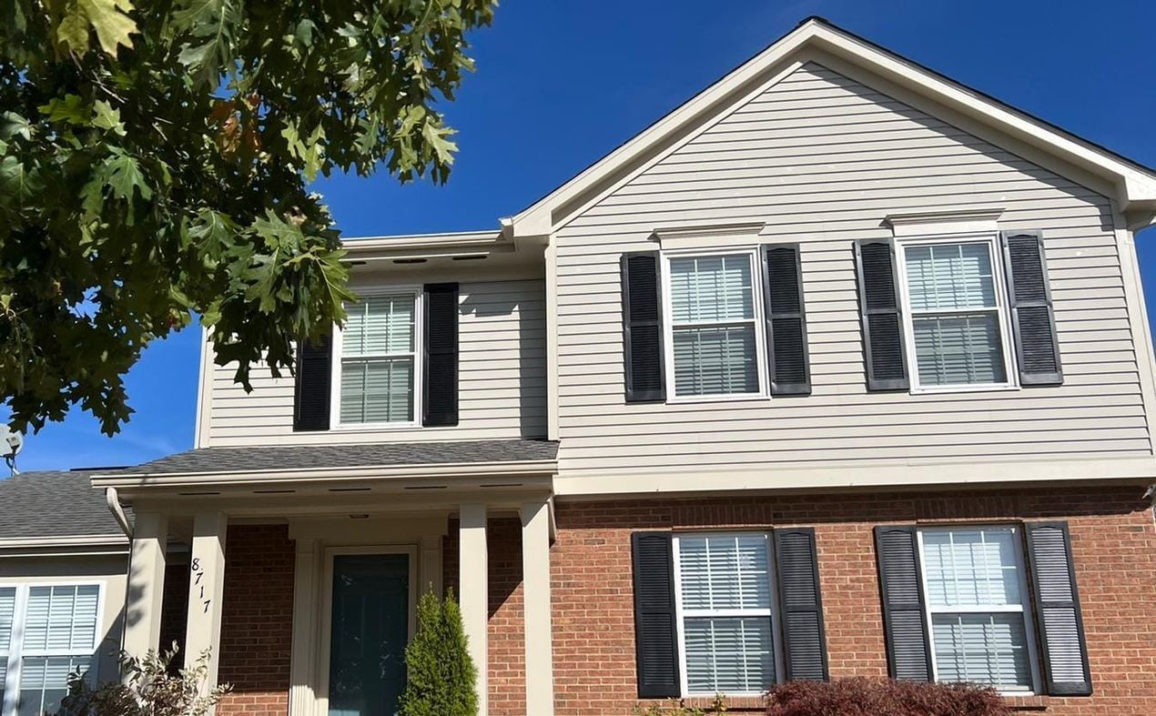 A large brick house with white siding and black shutters.