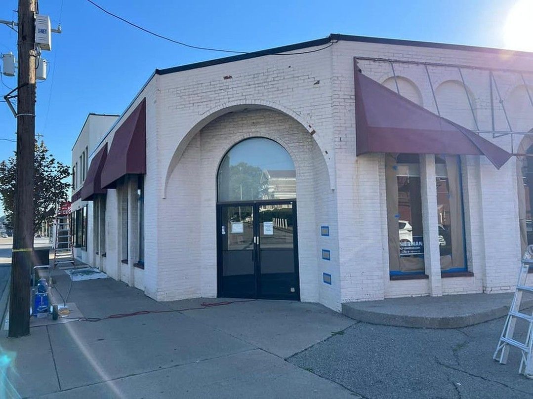 A white building with a red awning on the side of it.