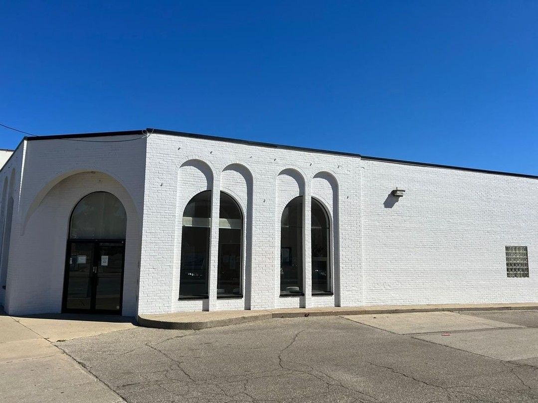 A white building with arched windows and a blue sky in the background.