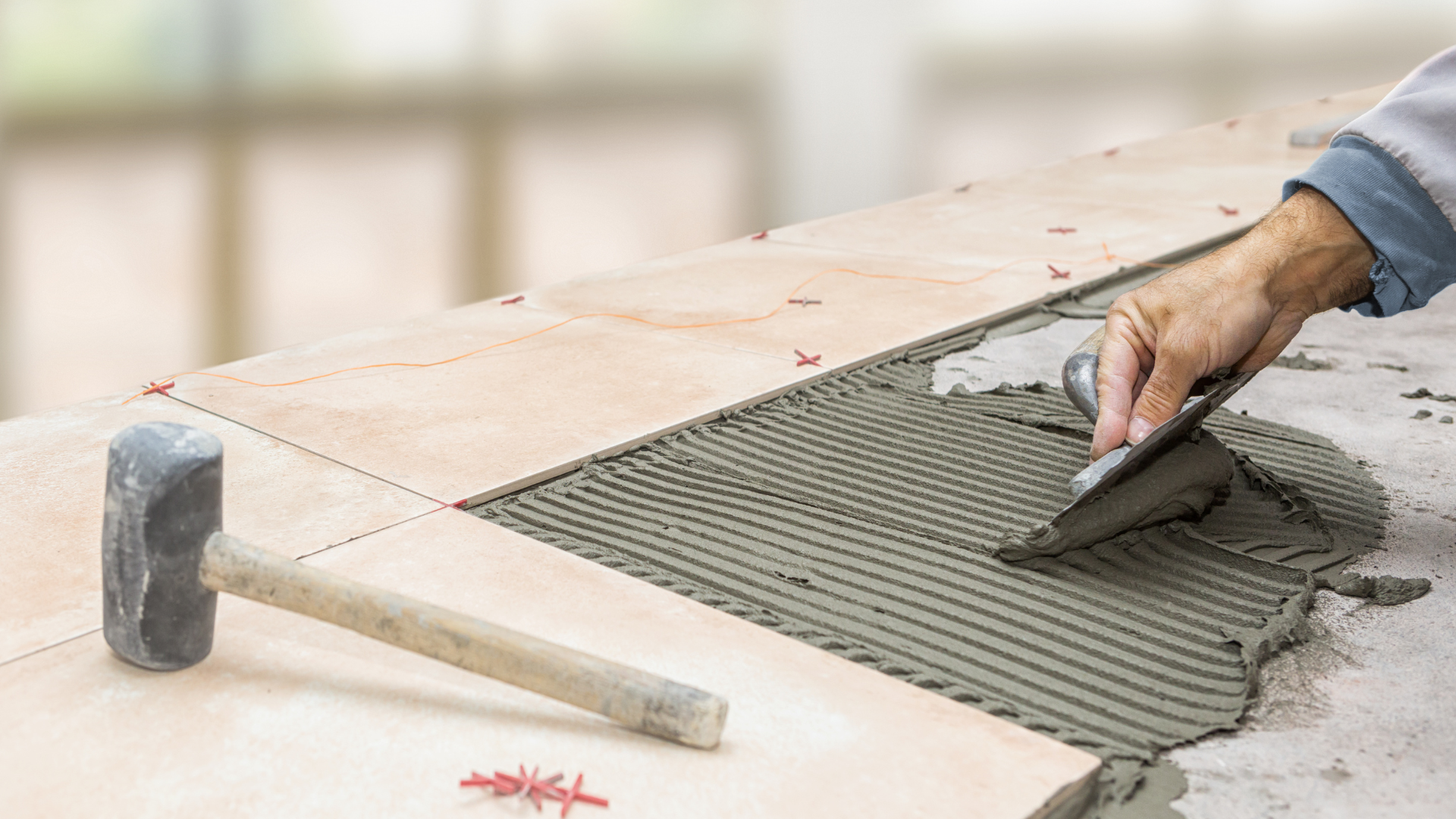 A person is laying tiles on a floor with a trowel.