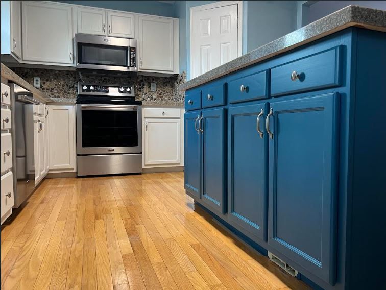 A kitchen with white cabinets , stainless steel appliances and blue walls