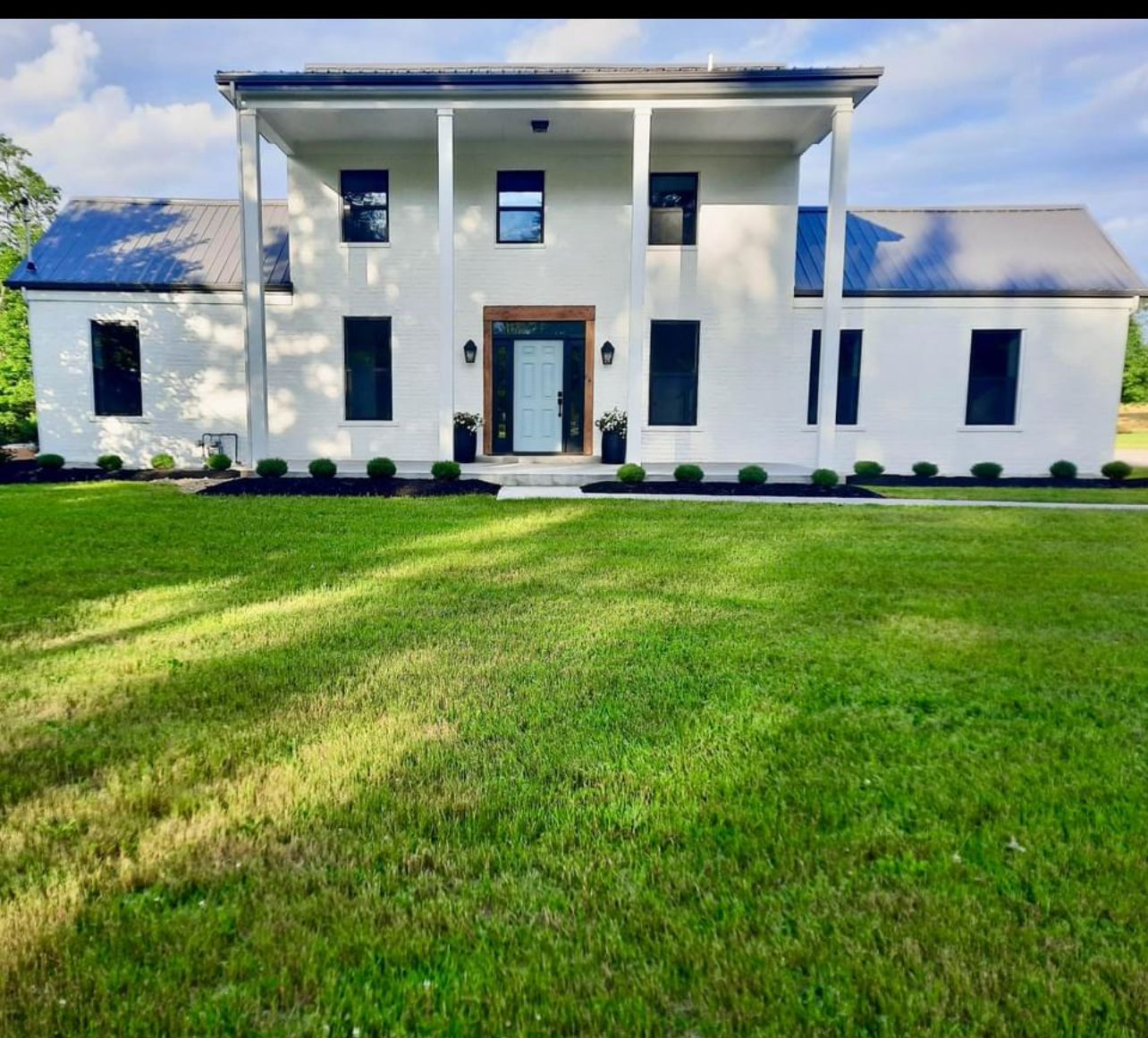 A large white house with a large lawn in front of it.