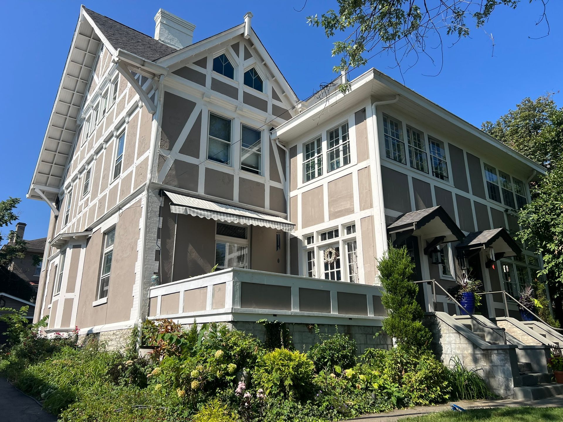 A large house with a lot of windows is surrounded by trees and bushes.