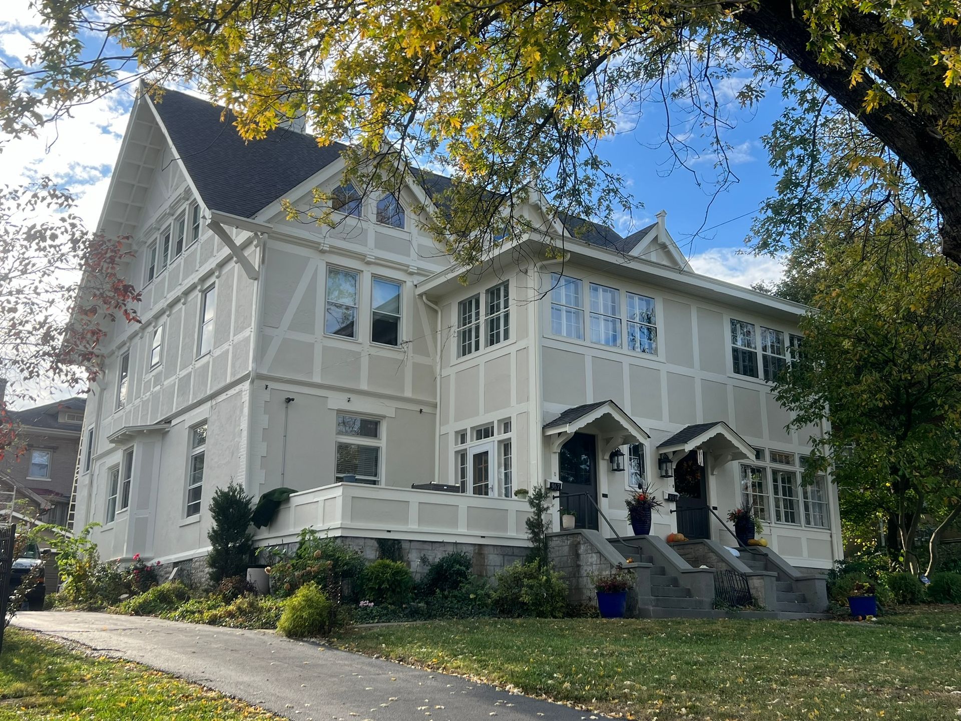 A large white house with a black roof is surrounded by trees.