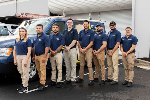 A group of men are posing for a picture in front of a van.