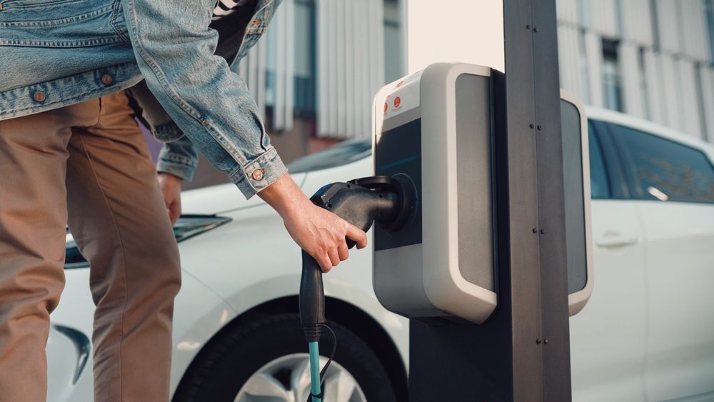 A man is charging his electric car at a charging station.