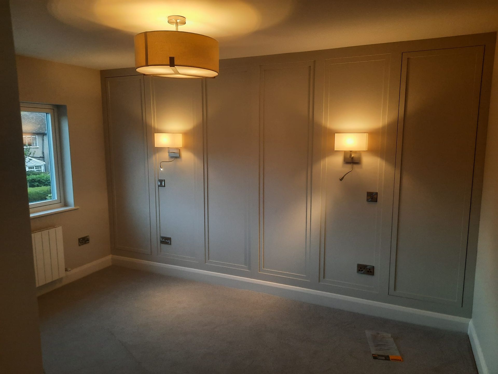 An empty room with a ceiling light and a window.