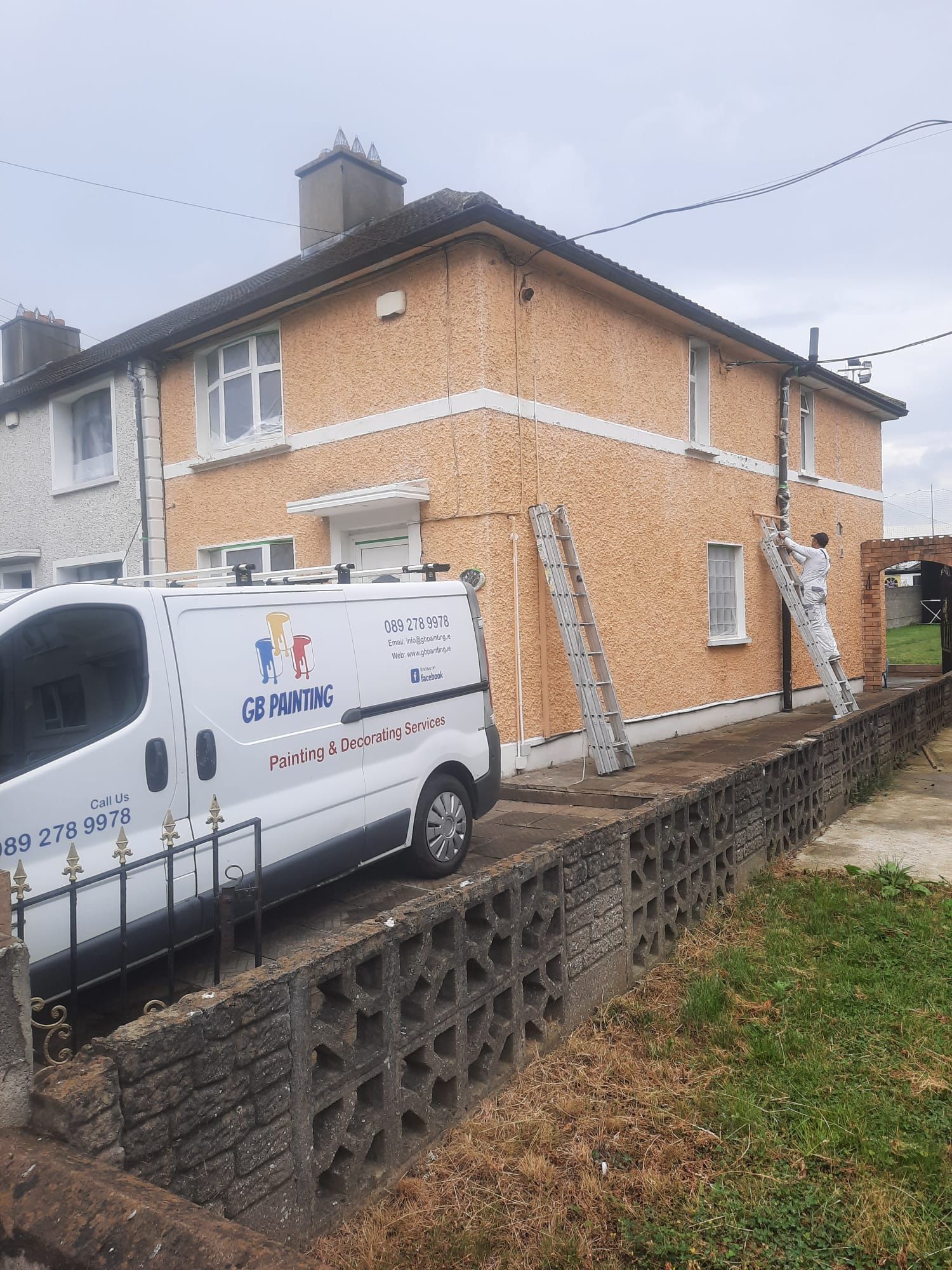A white van that says go painting is parked in front of a house