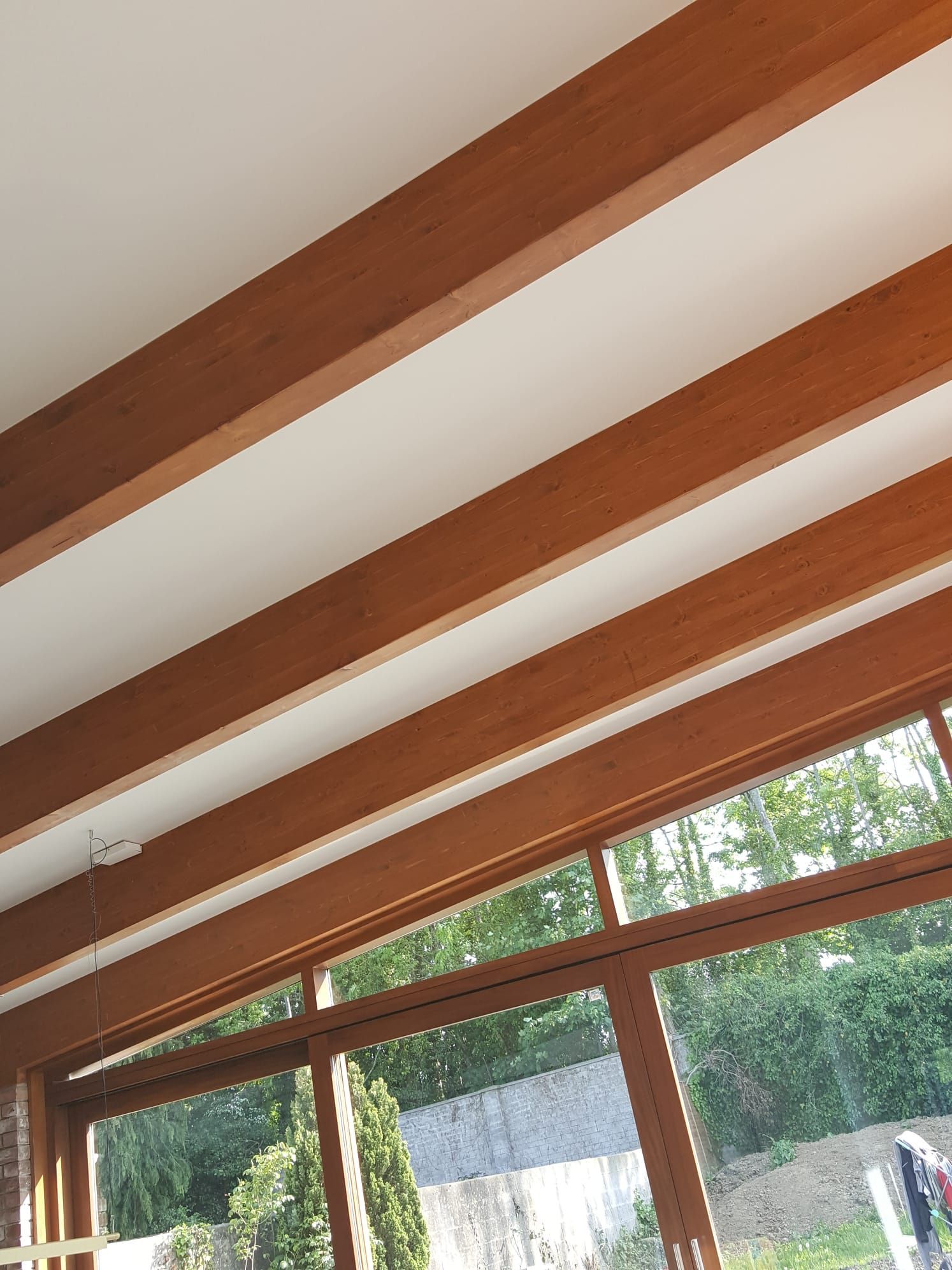 A room with a lot of windows and wooden beams on the ceiling