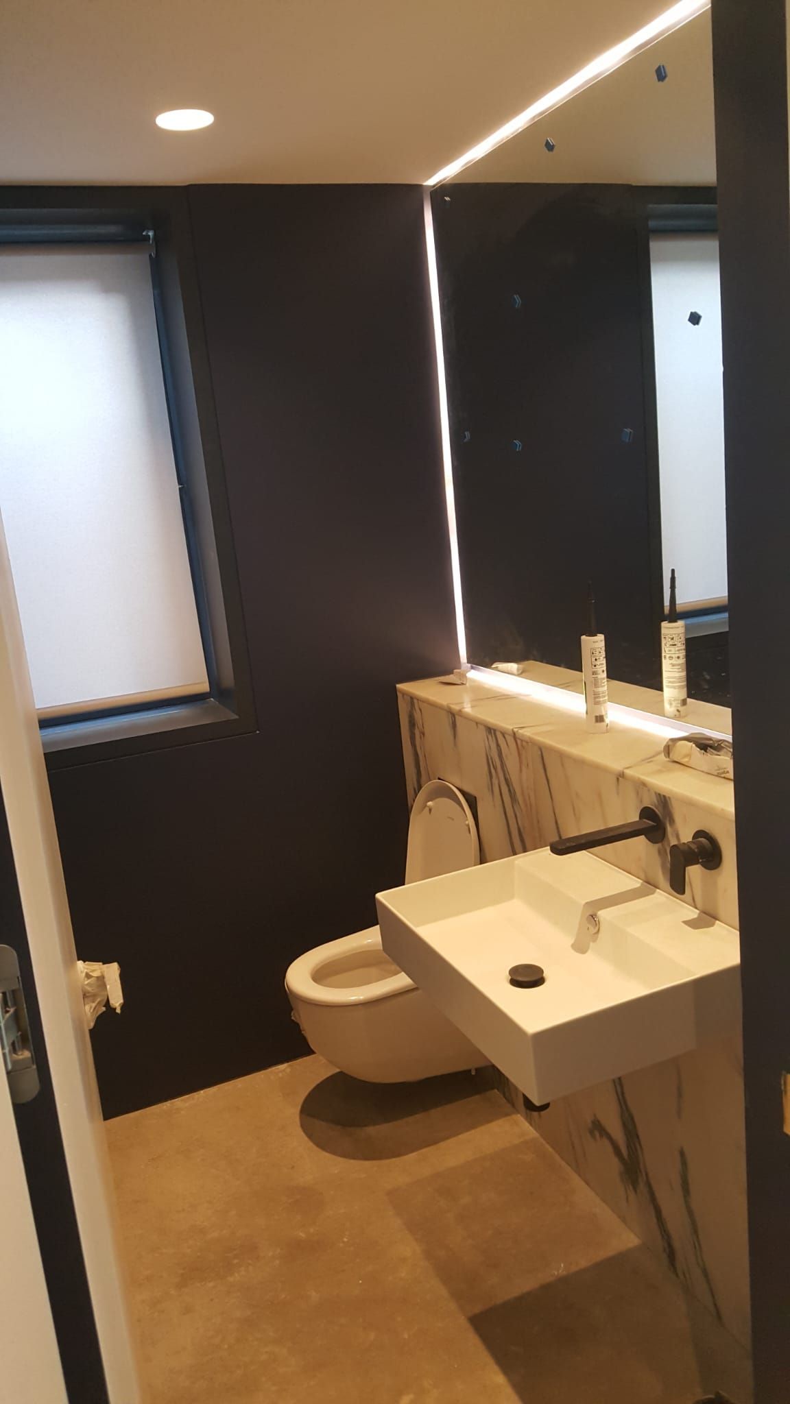 A bathroom with a toilet , sink and mirror.