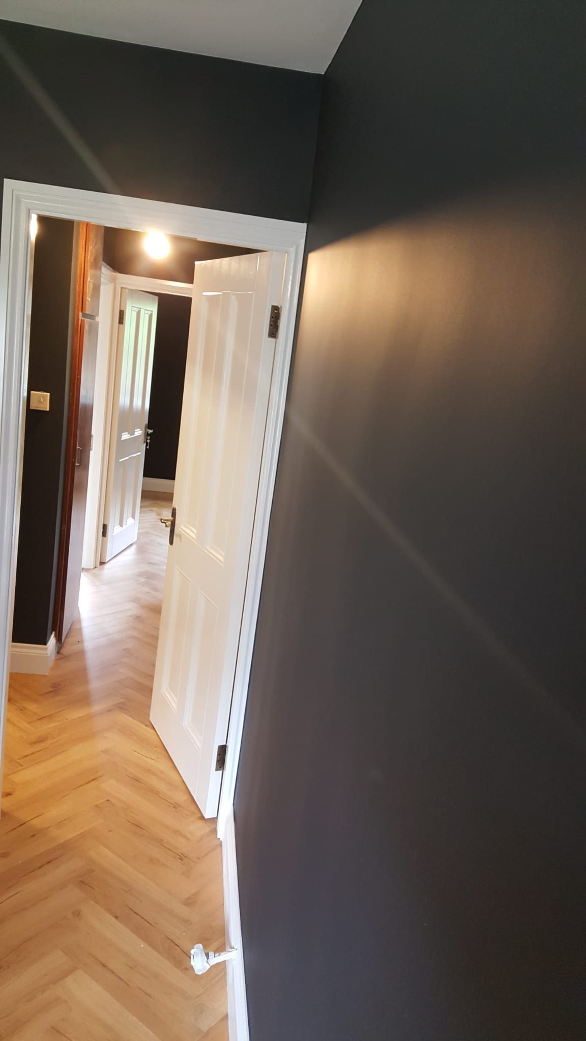 A hallway with a wooden floor and black walls.