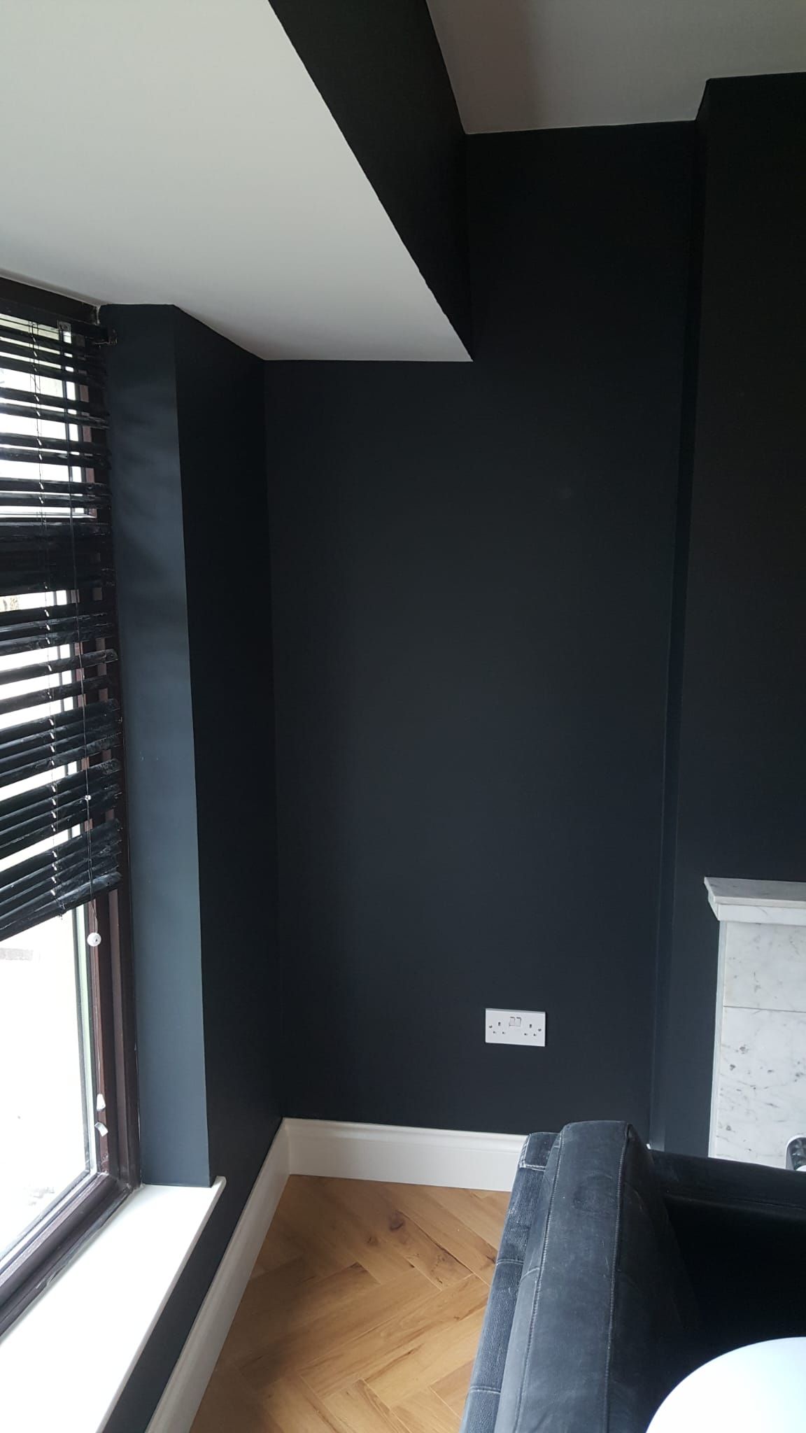 A living room with black walls and a fireplace.