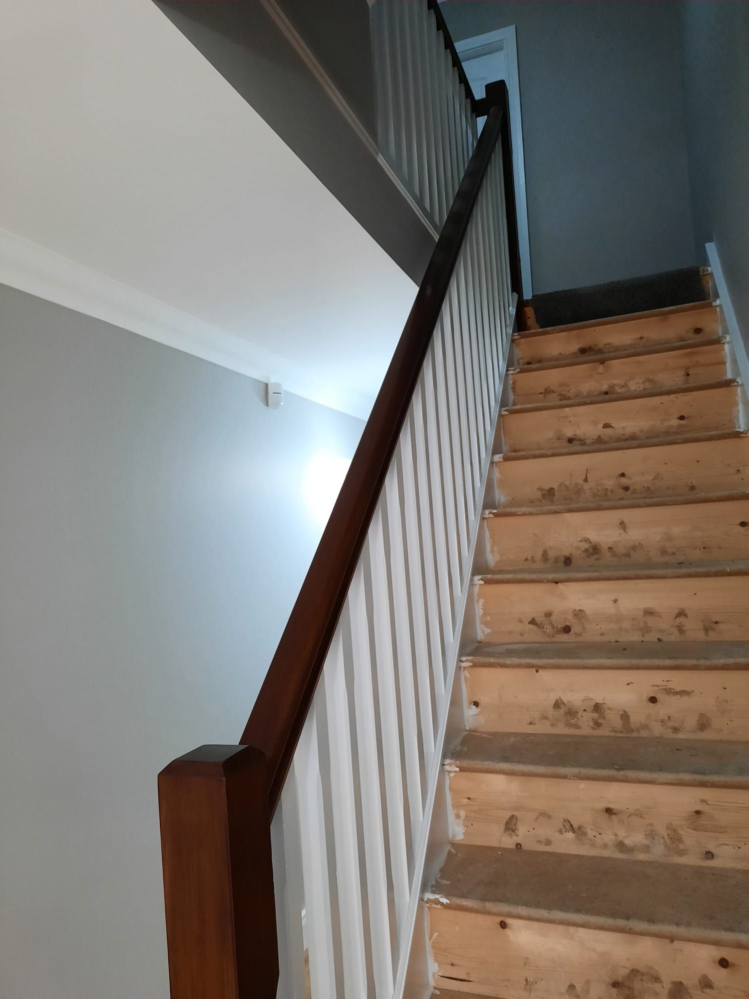 A wooden staircase with a white railing in a house.