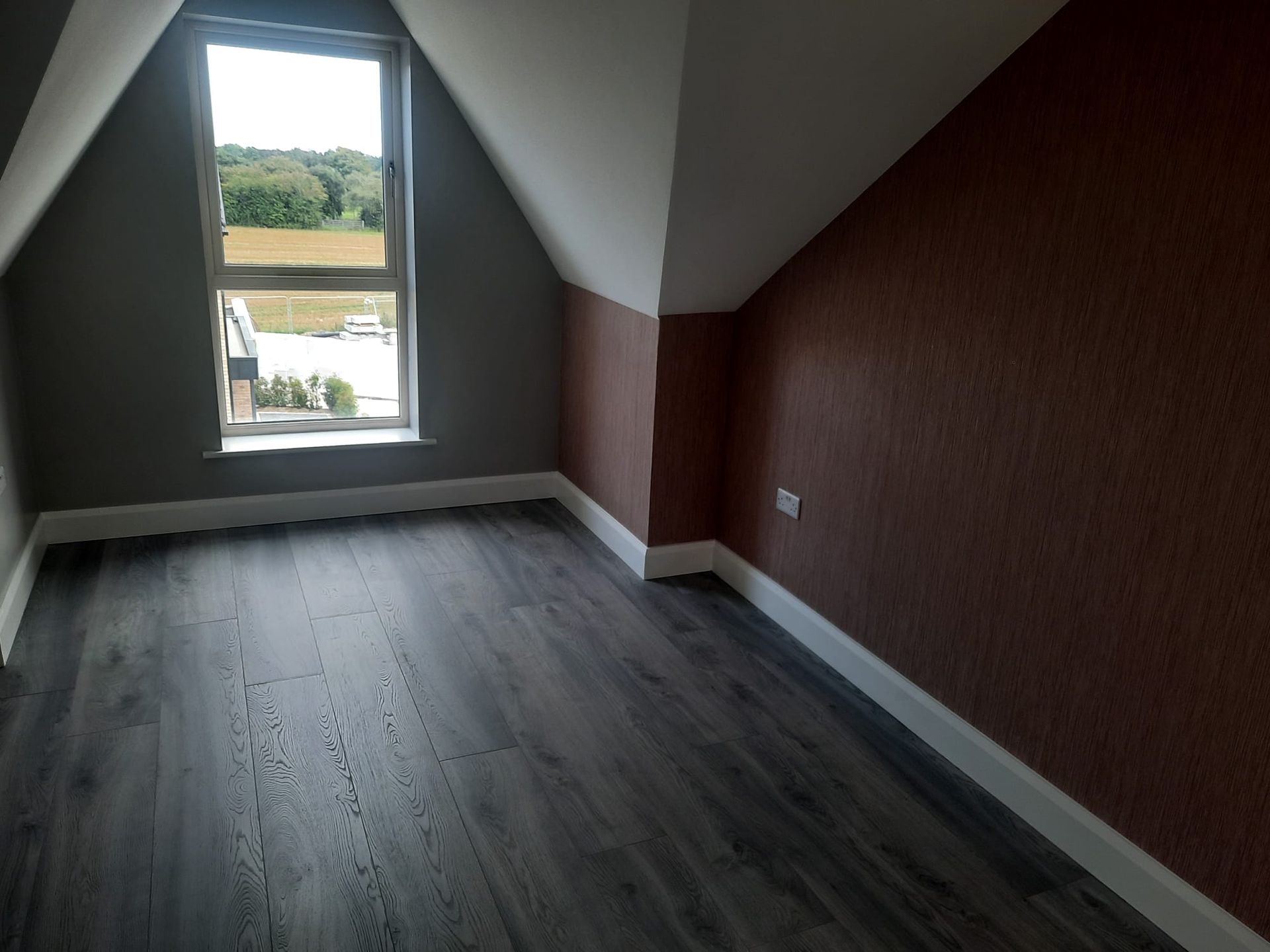 An empty room with a window and a wooden floor
