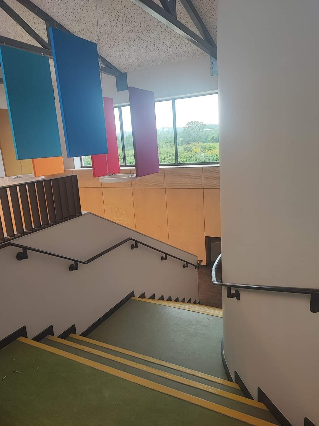 A staircase in a building with flags hanging from the ceiling