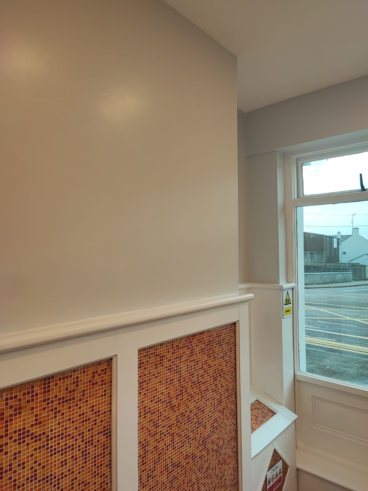 A room with white walls and a window with a view of a street.
