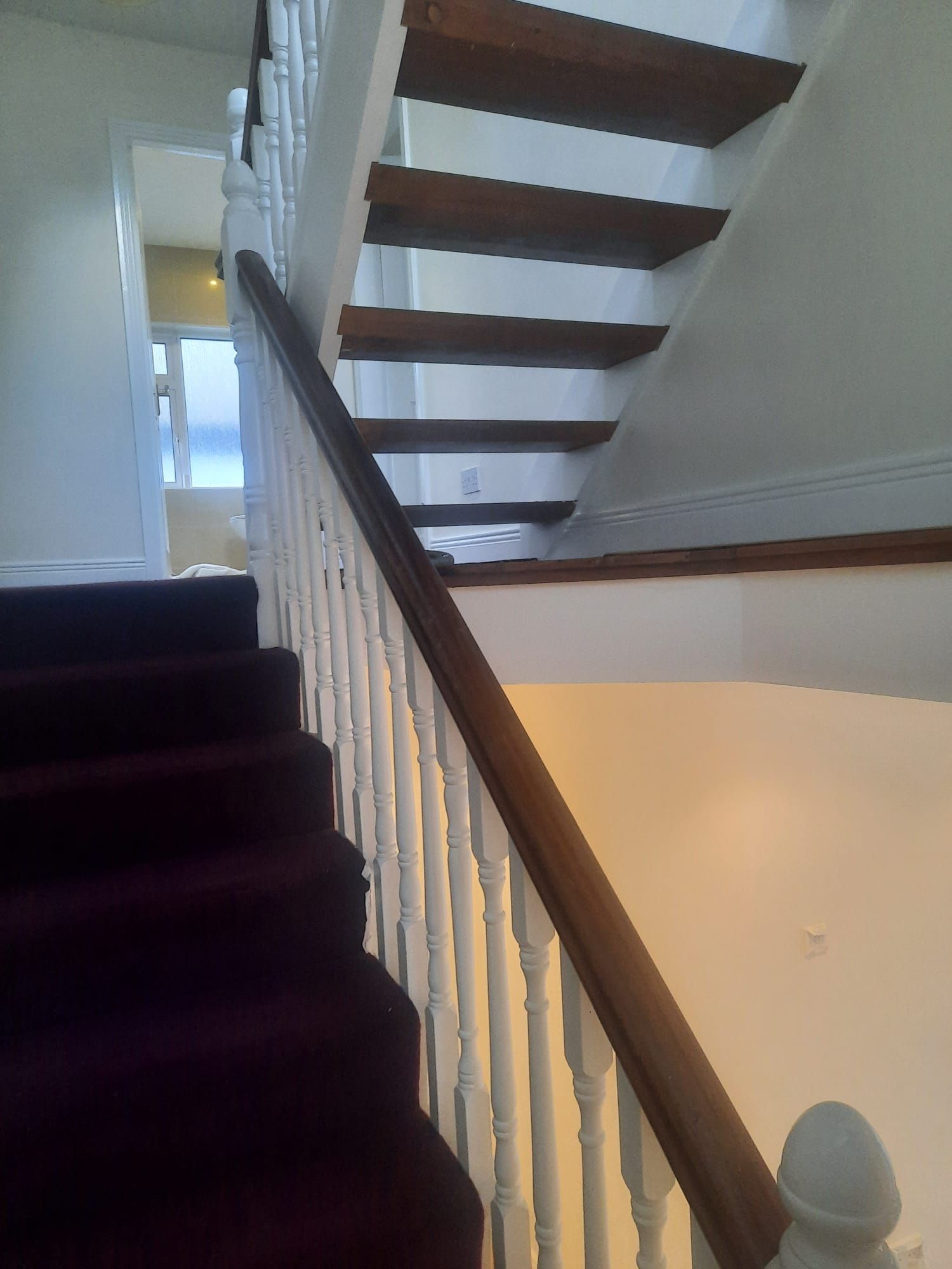 A staircase with a white railing and a purple carpet