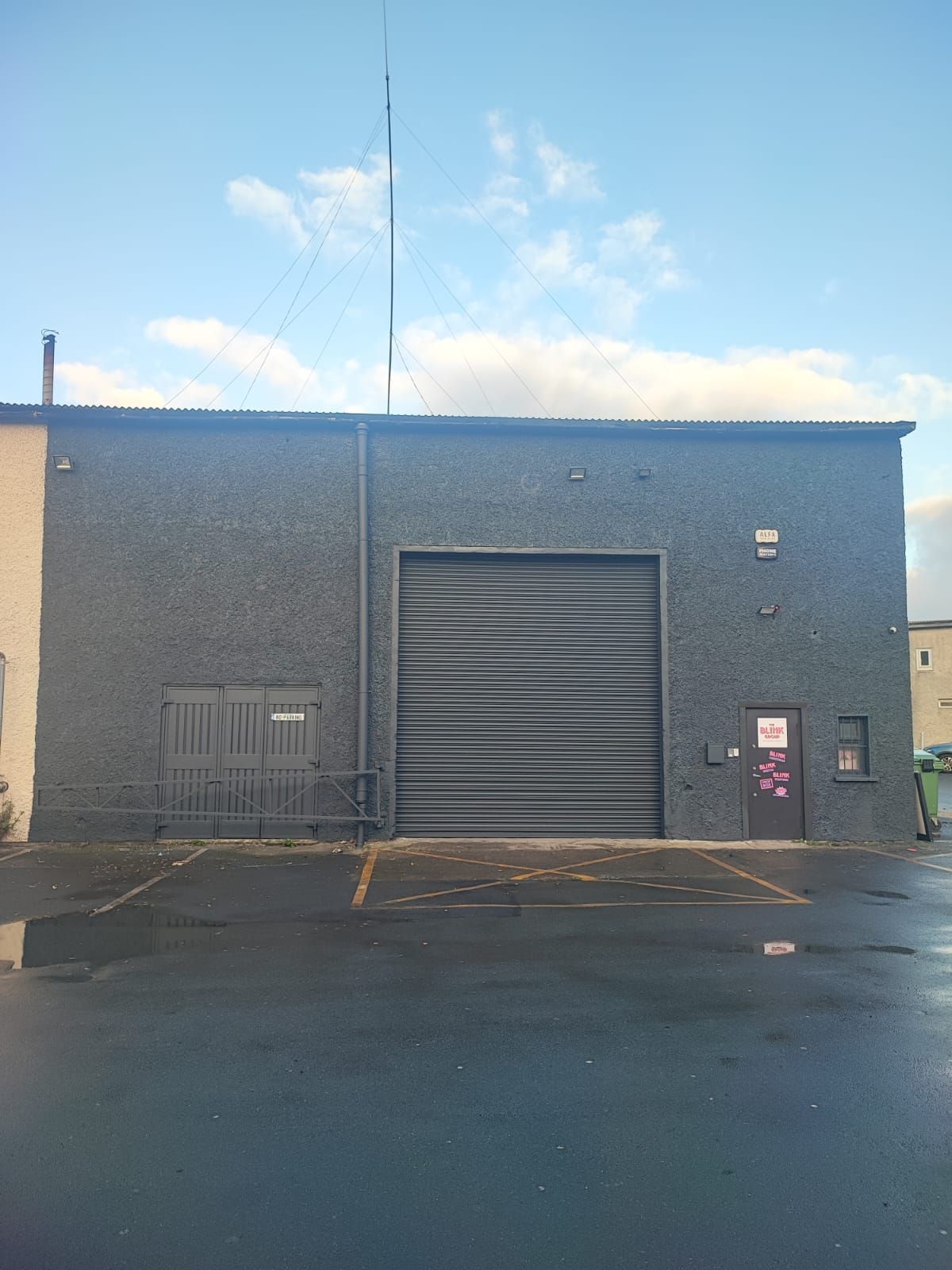 A building with a garage door and a parking lot in front of it.