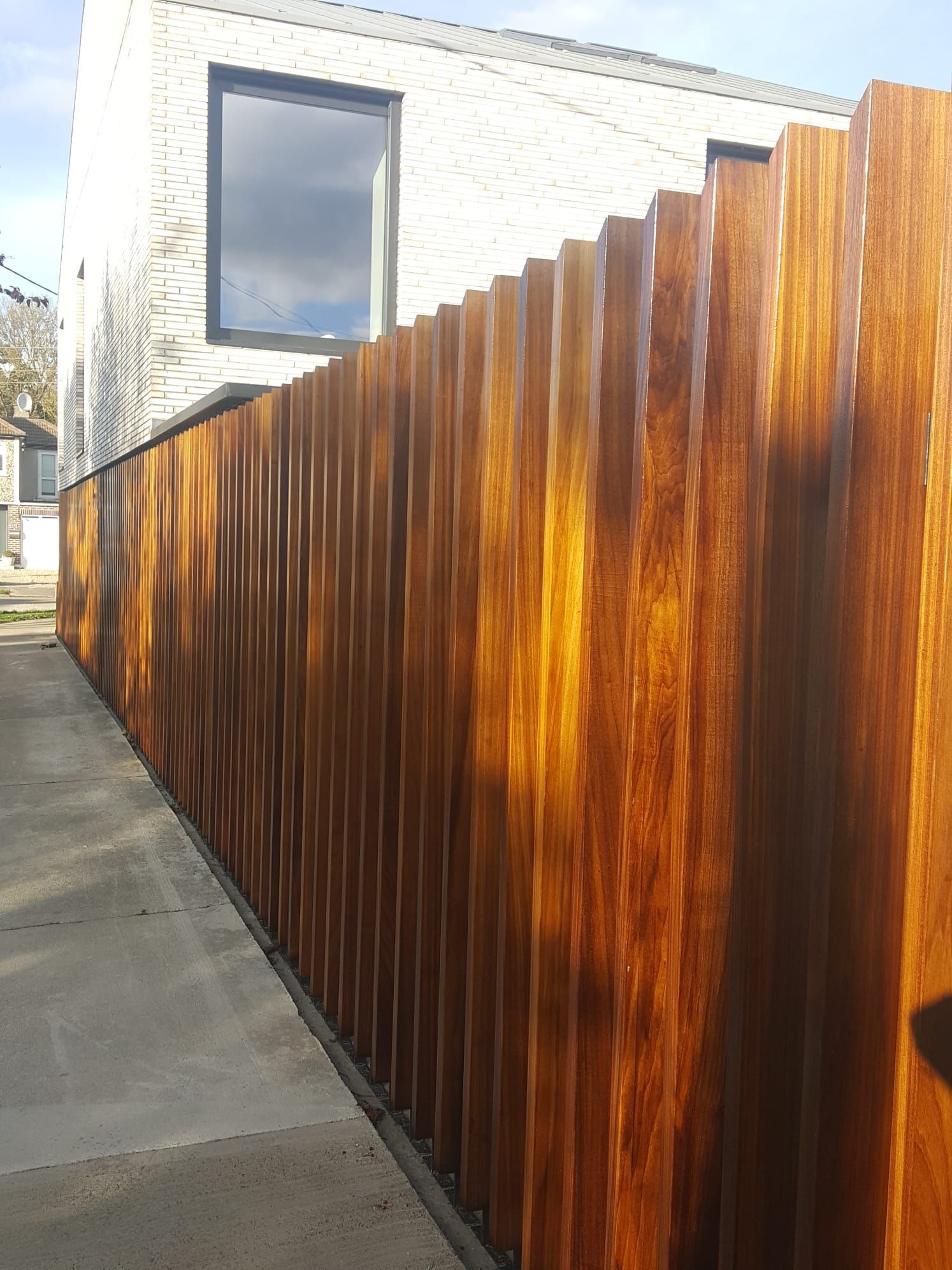 A wooden fence along a sidewalk next to a house.