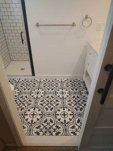 Small bathroom with patterned black and white floor tiles, white walls, and a shower.