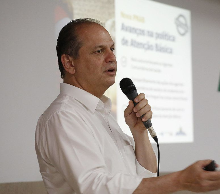 Um homem de camisa branca está falando em um microfone