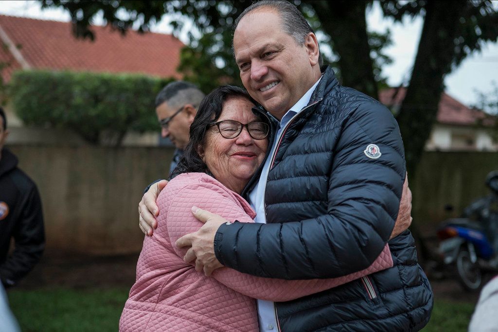 Um homem está abraçando uma mulher em um parque.