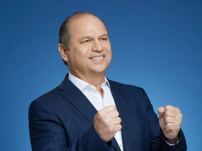 Um homem de terno e camisa branca está erguendo o punho no ar.