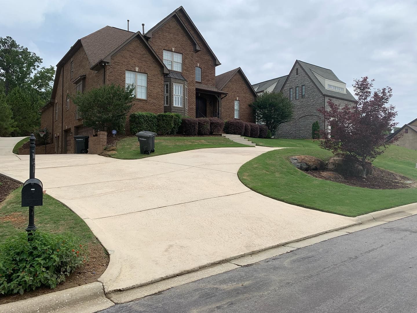A large brick house with a long driveway and a mailbox in front of it.