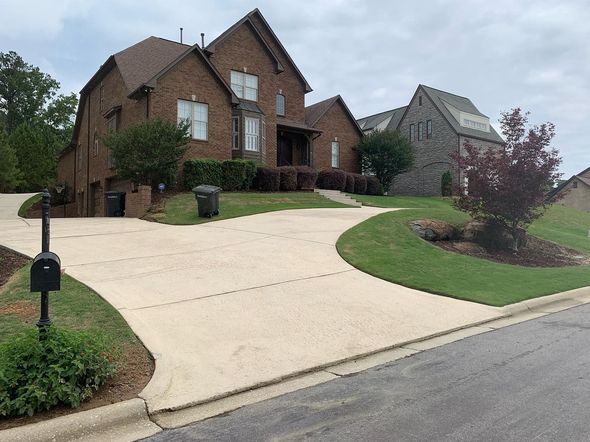A large brick house with a long driveway and a mailbox in front of it.
