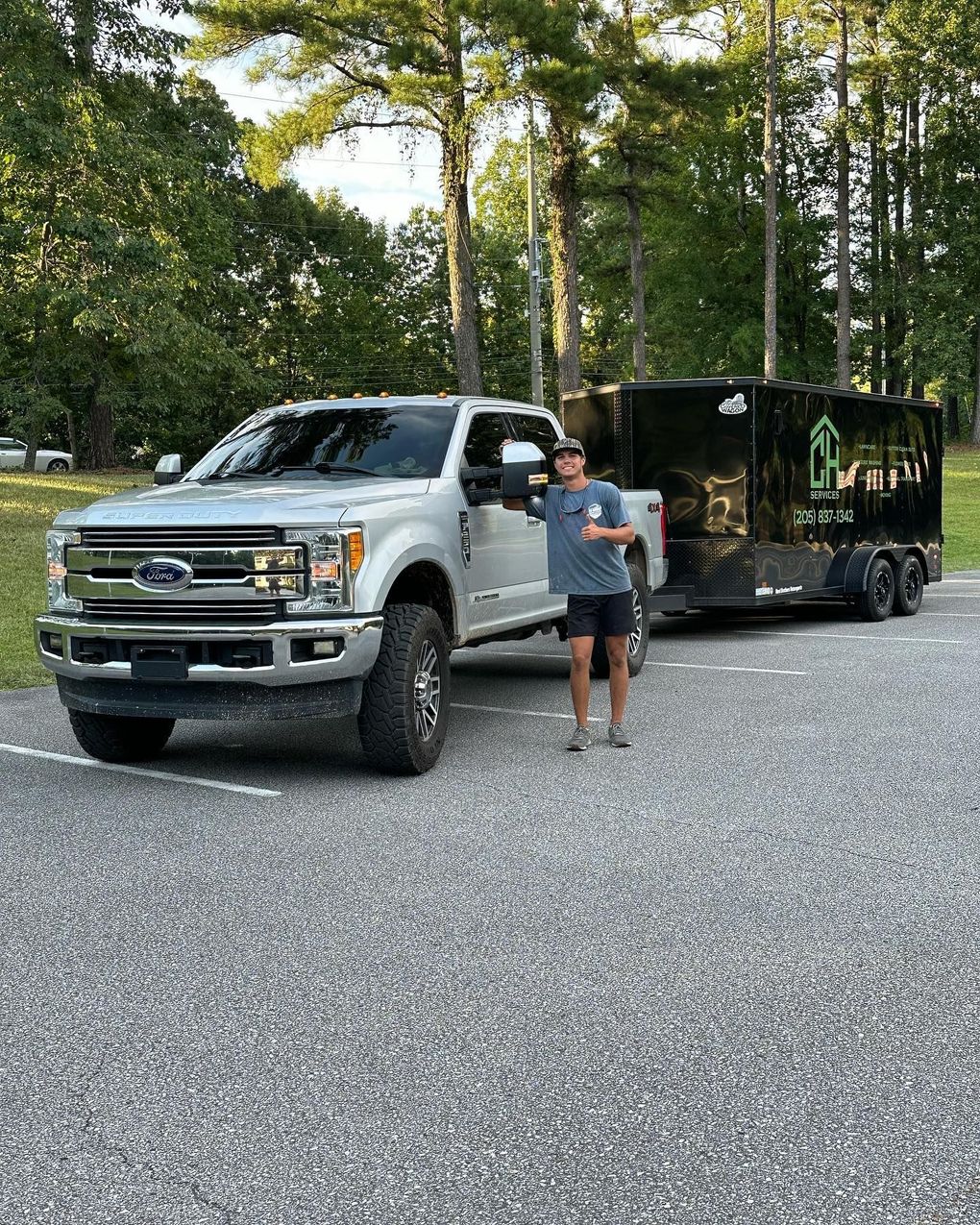 A man is standing in front of a truck and trailer.