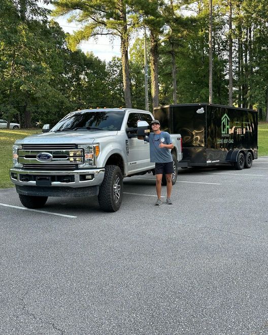 A man is standing in front of a truck and trailer.
