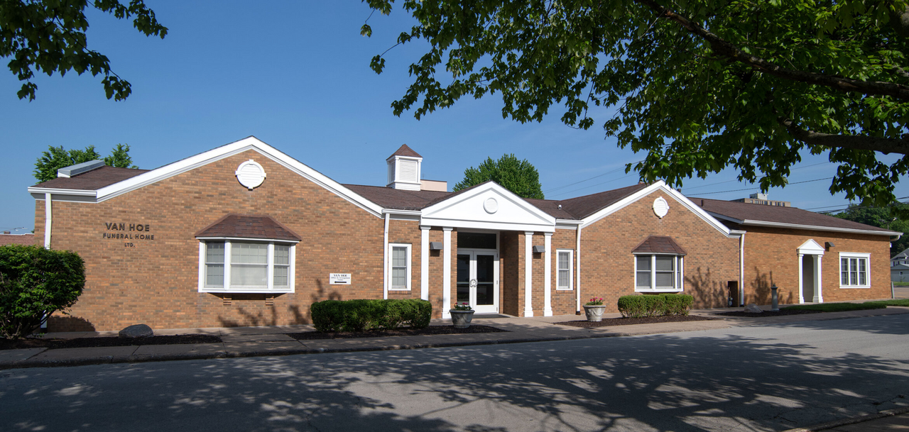 A brick building with white trim, arched windows, and a small cupola under a clear blue sky.