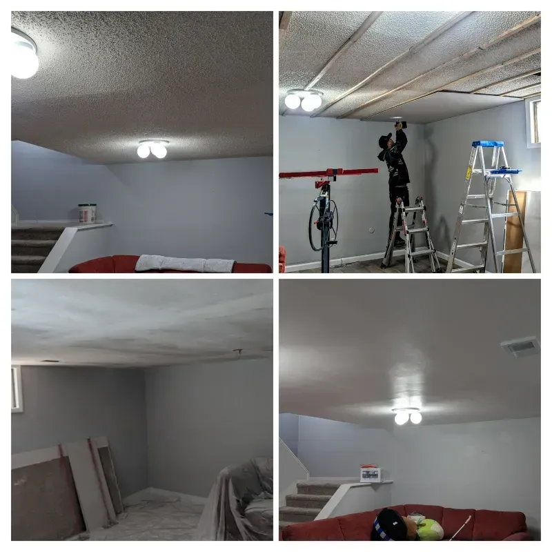 Renovating a basement: a person on ladders installs boards on the ceiling. Gray walls, white ceiling, and stairs are visible.