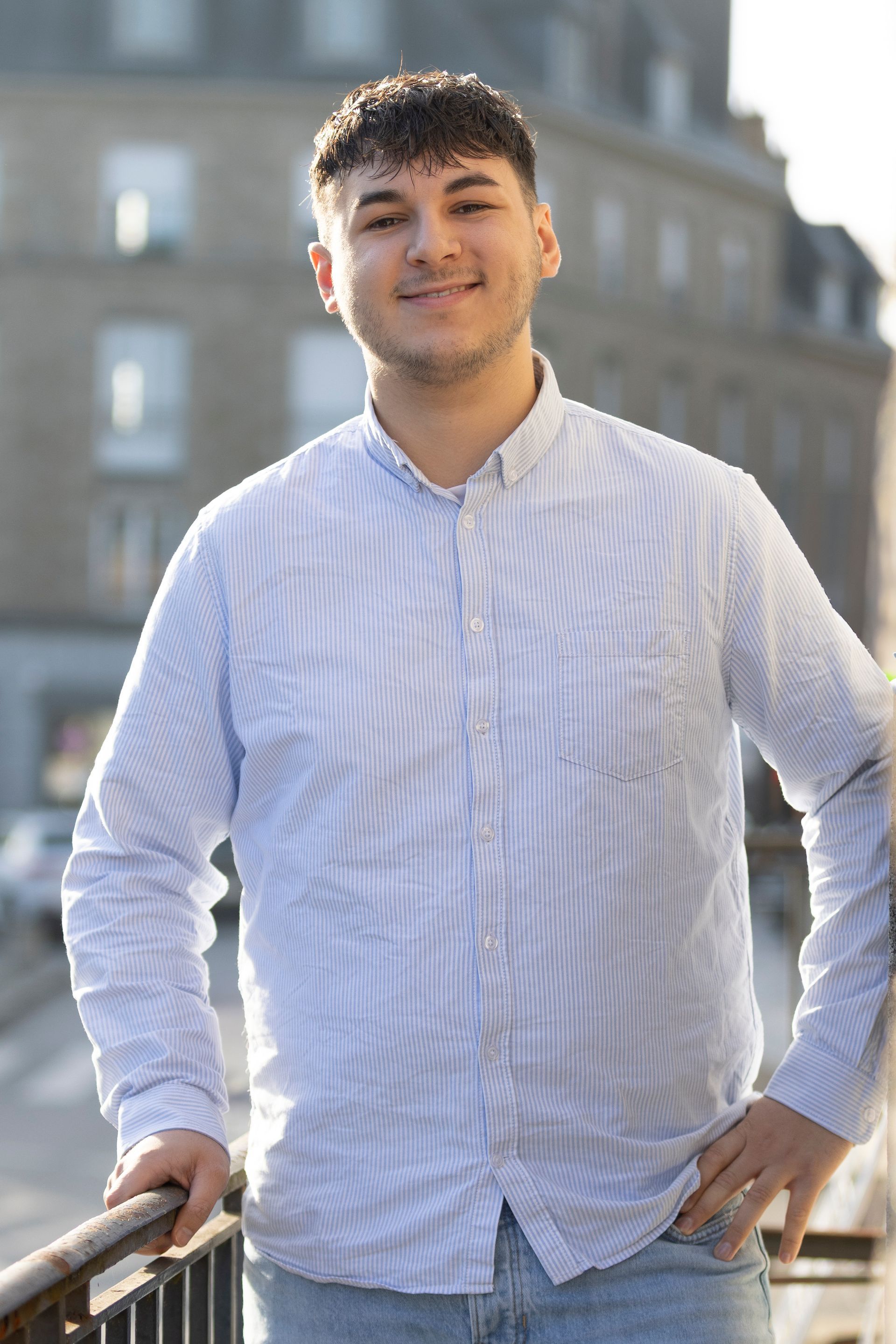 Une personne en costume tenant une maison en papier et des clés sur une table en bois.