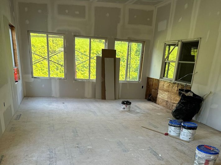 An empty room with a lot of windows and buckets of paint.