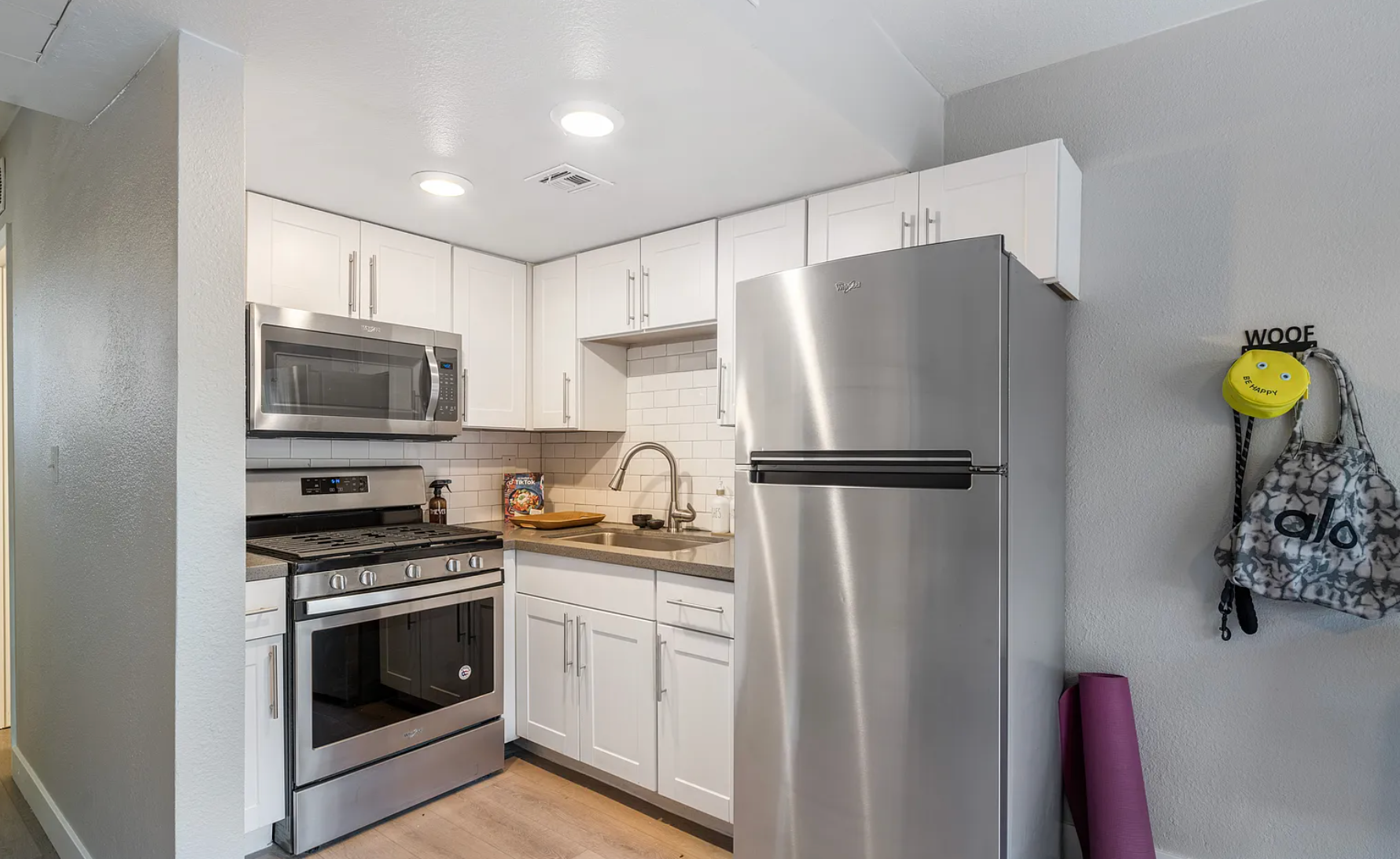 Small kitchen with white cabinets, stainless steel appliances, and a gray wall.