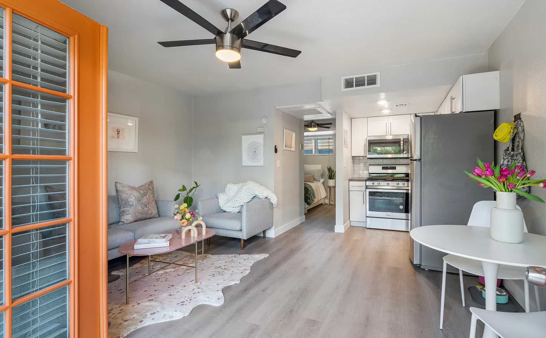 Small, open-concept apartment with a sofa, table, and kitchen; natural light.