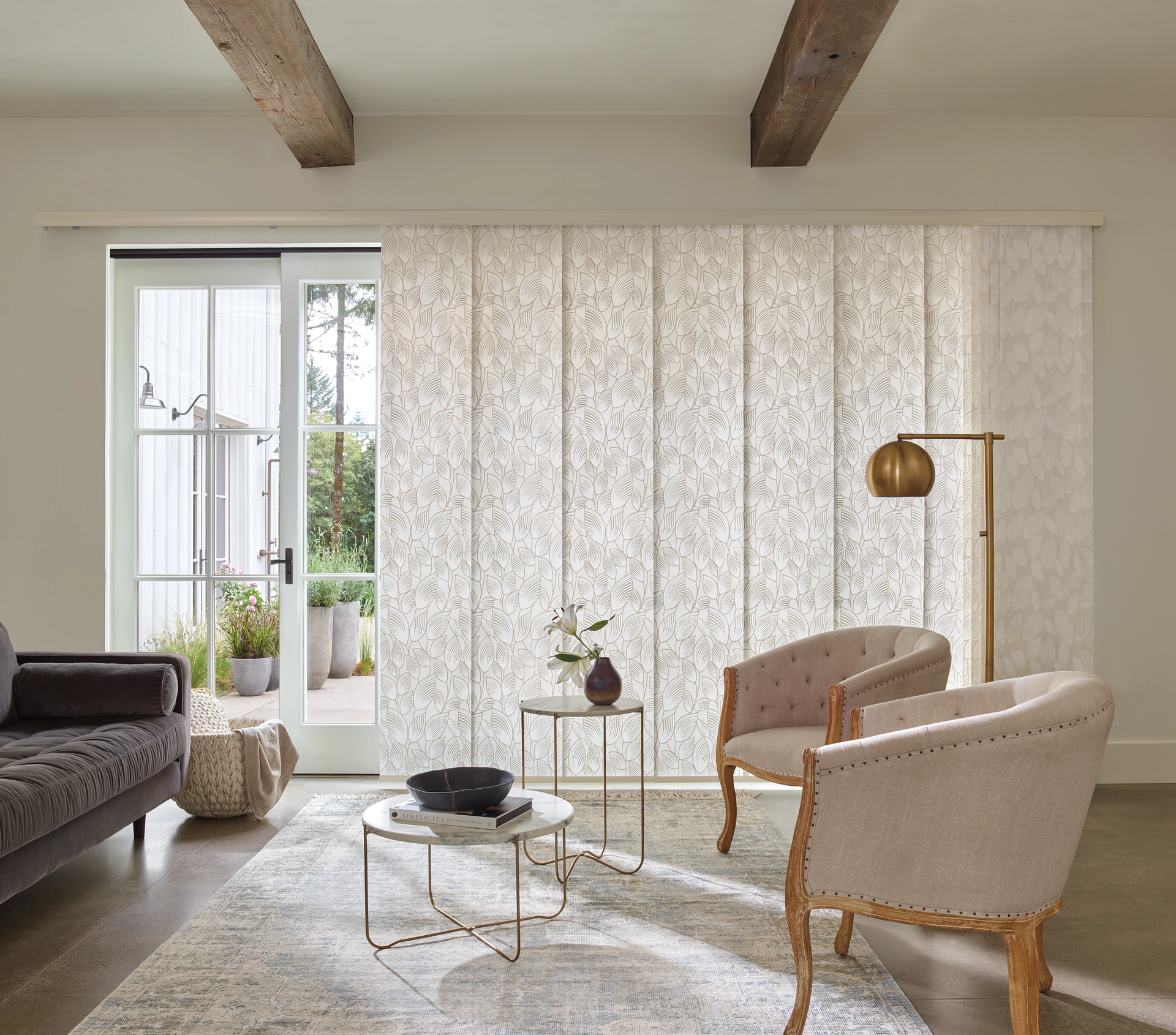 Bright living room with beige chairs, a sofa, rug, coffee table, floor lamp, and sheer curtains.