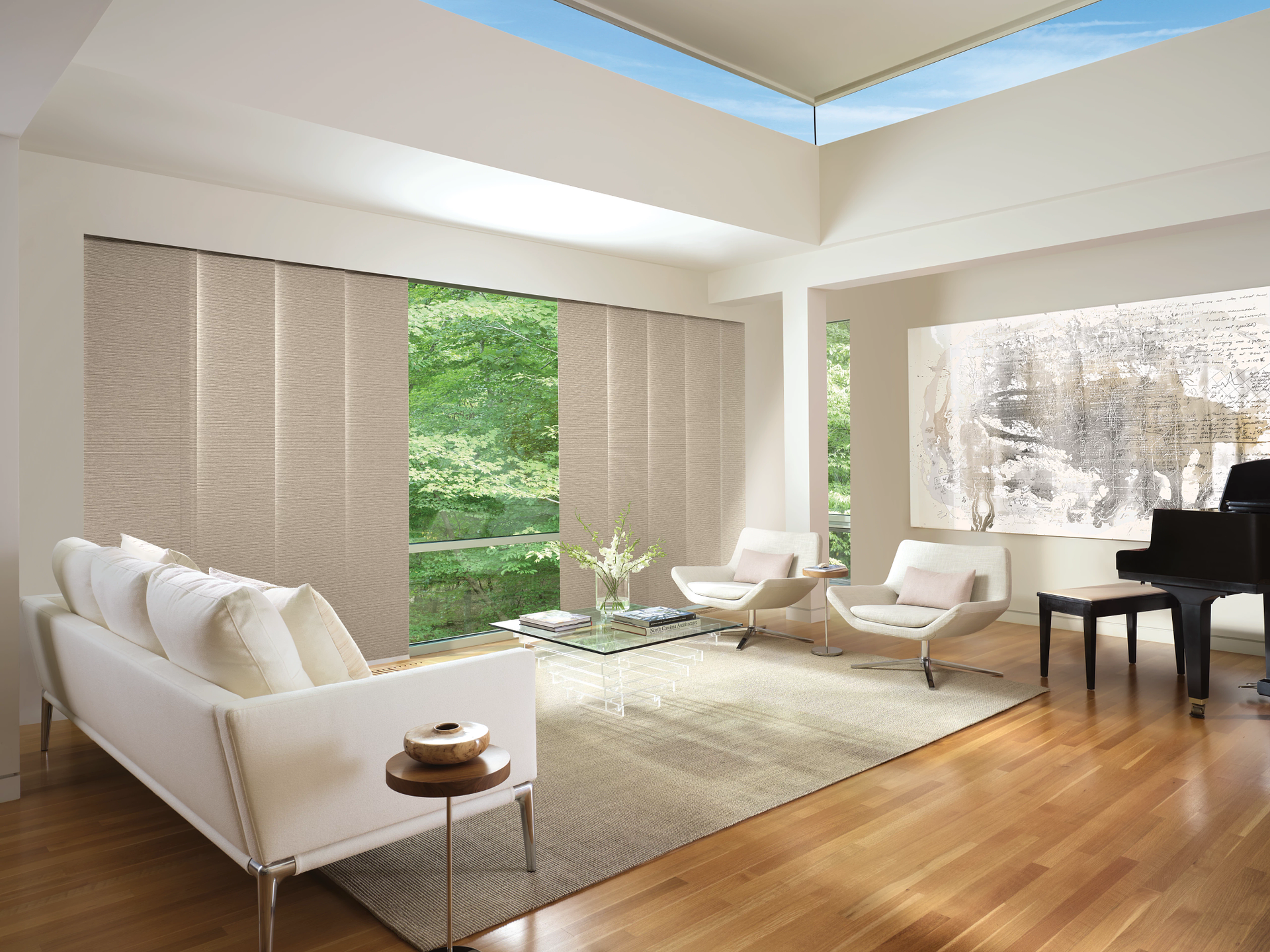 Modern living room with white chairs, beige rug, piano, and large windows overlooking greenery