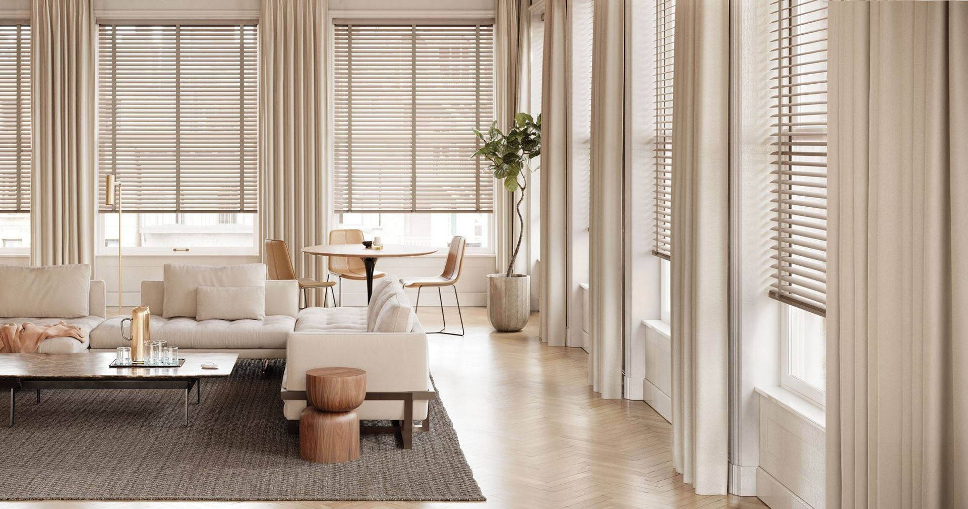 Bright minimalist living room with beige sofa, coffee table, rug, and large windows with blinds