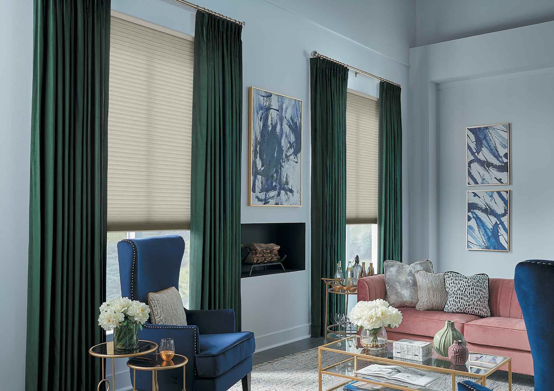 Elegant living room with blue armchairs, pink sofa, tall windows, and wall art.