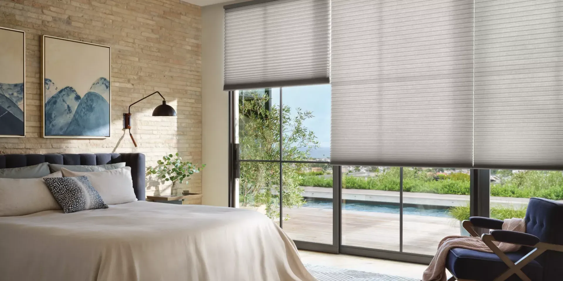 Bright bedroom with a large bed, floor-to-ceiling windows, and a balcony view of greenery and water.