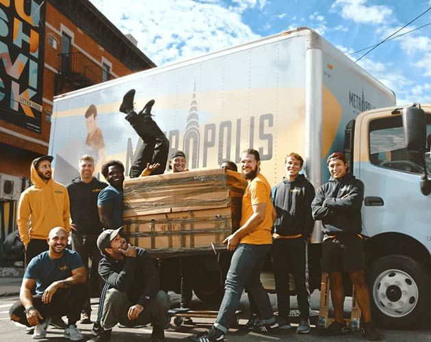 A group of men are posing for a picture in front of a moving truck.