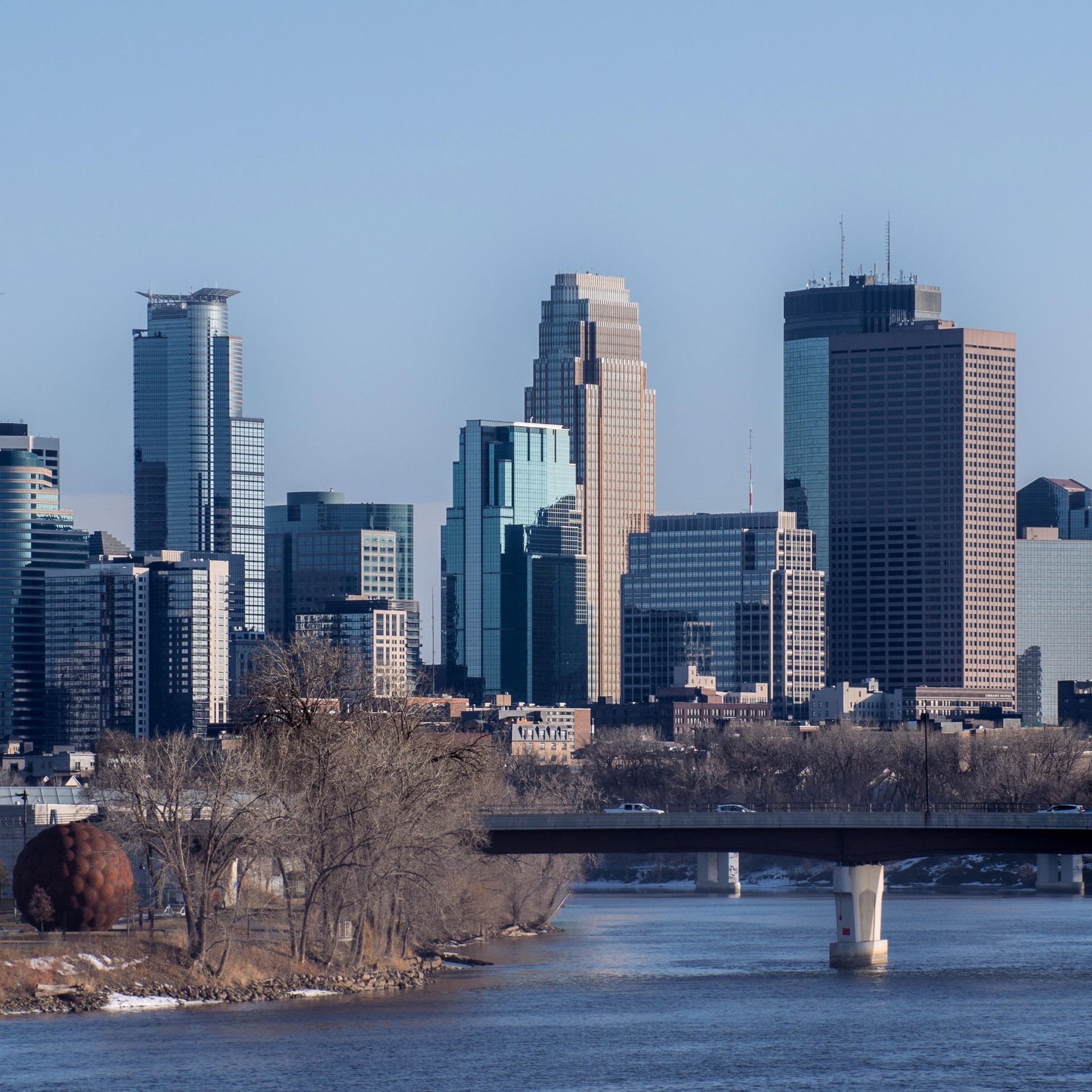 A bridge over a river with a city skyline in the background