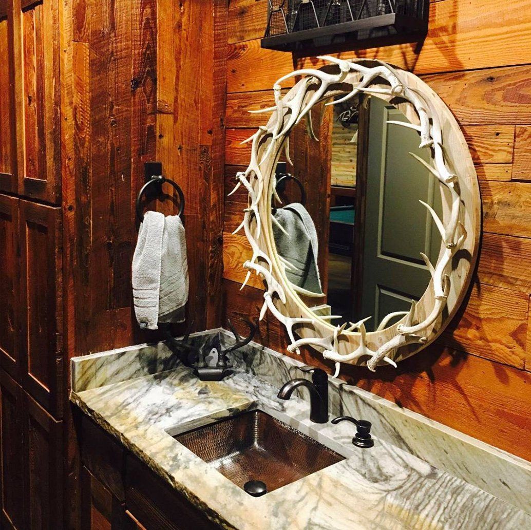A mirror in a bathroom circled by deer antlers